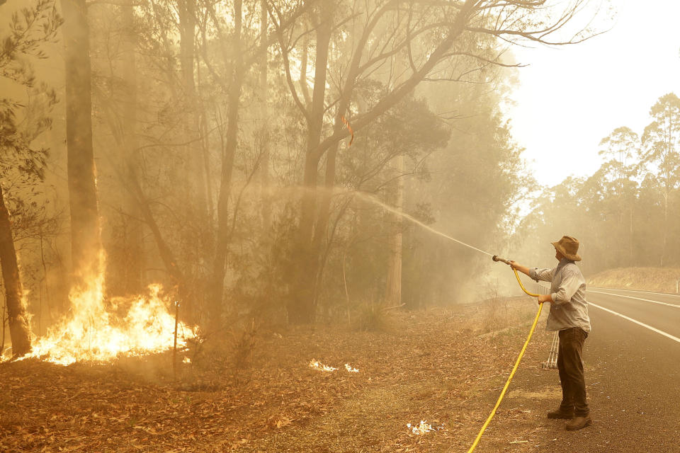 A man uses a water hose to battle a fire near Moruya, near where Michael Clarke was killed on Thursday. Source: AAP 