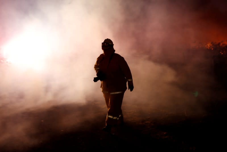 A photographer walks in a cloud of smoke during the wind-driven Kincade Fire in Healdsburg