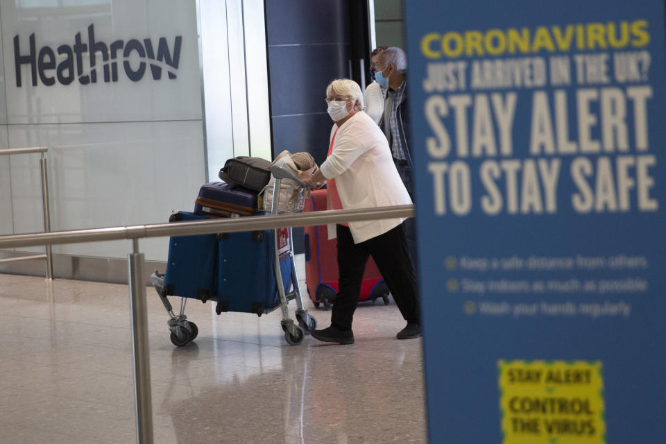 Passengers wearing face masks arrive on the first day of new rules that people arriving in Britain from overseas will have to quarantine themselves for 14 days to help stop the spread of coronavirus, at Heathrow Airpot in London, Monday, June 8, 2020. The British government has said that anyone caught not complying with the quarantine will face a fine. (AP Photo/Matt Dunham)