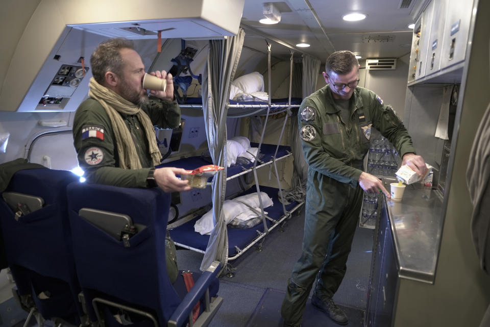 Crew members break for refreshments in the galley of a French military AWACS surveillance plane as it flies a 10-hour mission Tuesday, Jan. 9, 2024, to eastern Romania for the NATO military alliance. France's four AWACS are among a variety of surveillance aircraft, including unmanned UAV drones, that gather intelligence for NATO and its member nations (AP Photo/John Leicester)