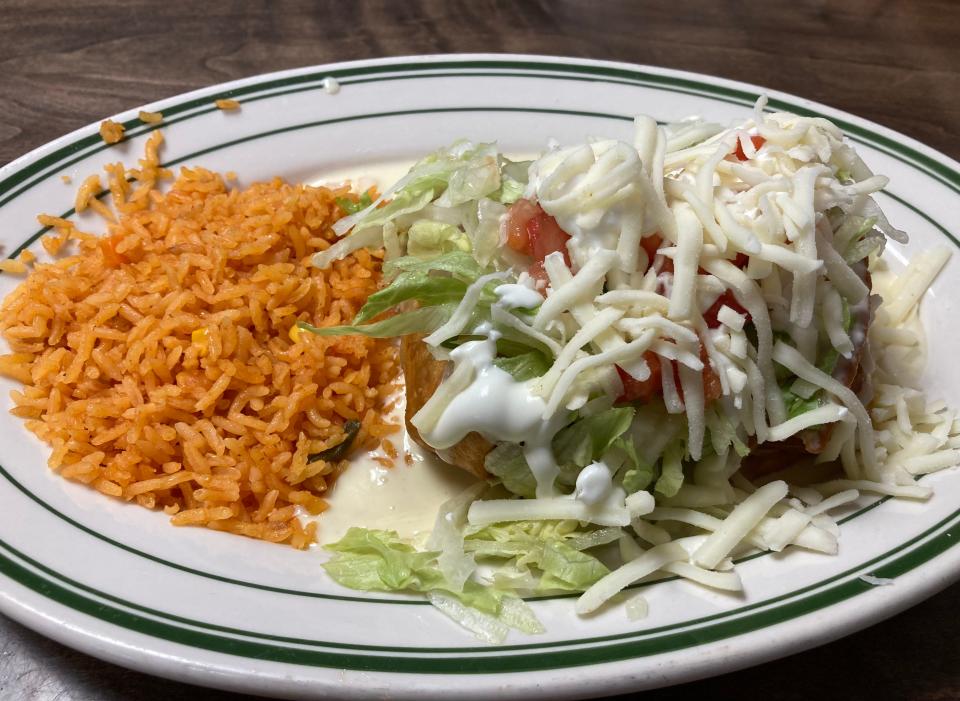 Chimichangas - two deep-fried tortillas filled with carnitas (pork) and topped with lettuce, tomato, sour cream, beans and cheese dip - are served with a side of rice at La Loma.