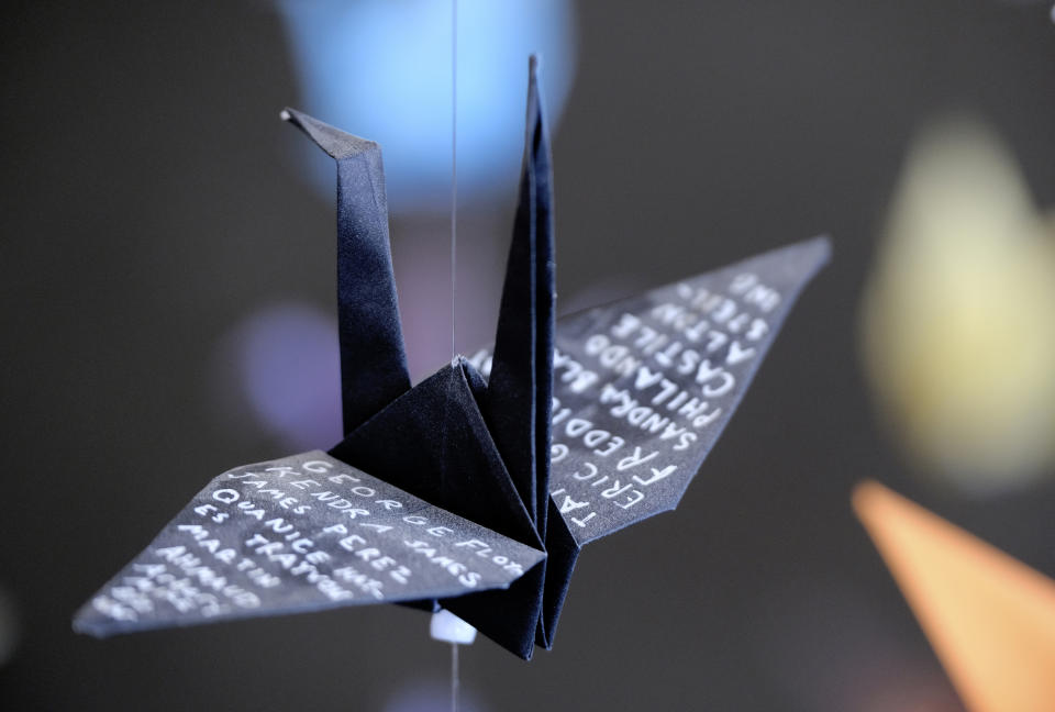 An origami paper crane with the names of victims of police violence hangs with thousands of other cranes in an exhibit for those who have died in the U.S., from COVID-19, on Tuesday, Aug. 11, 2020. Karla Funderburk started making the cranes three months earlier, stringing the paper swans in pink, blue, yellow and many other colors together and hanging them in her gallery. (AP Photo/Richard Vogel)