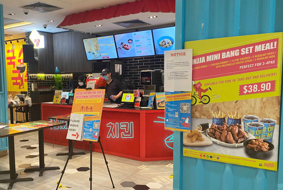 A poster on social distancing and coronavirus tracing app is placed at the entrance of a restaurant Wednesday, May 19, 2021 in Singapore. Across much of Asia, taxi drivers are starved for customers, weddings are suddenly canceled, schools are closed, and restaurant service is restricted as the coronavirus comes surging back in countries where it had seemed to be well under control. (AP Photo/Zen Soo)