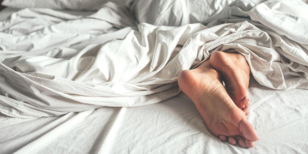 Woman rubbing feet together in bed