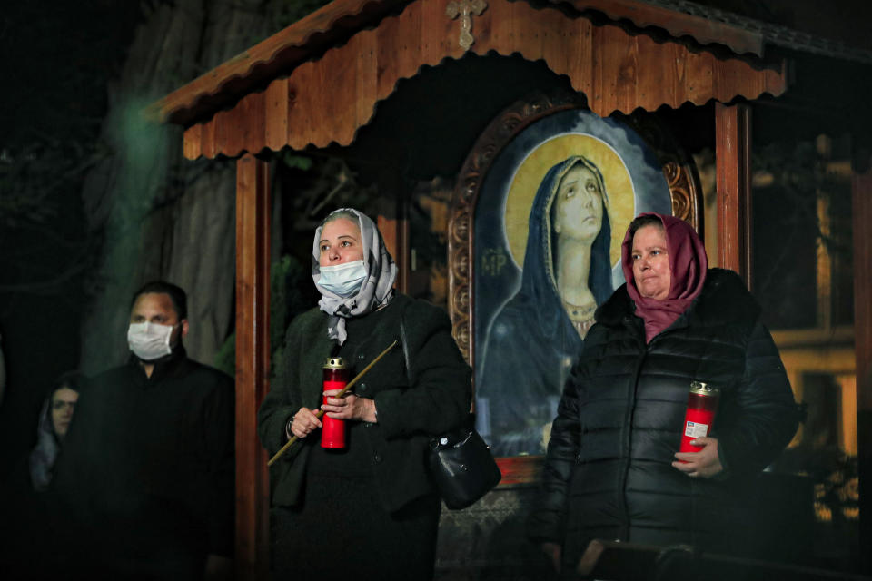 Orthodox worshipers, some wearing masks for protection against the COVID-19 virus, wait for a religious service in the Black Sea port of Constanta, Romania, late Tuesday, May 26, 2020. (AP Photo/Vadim Ghirda)