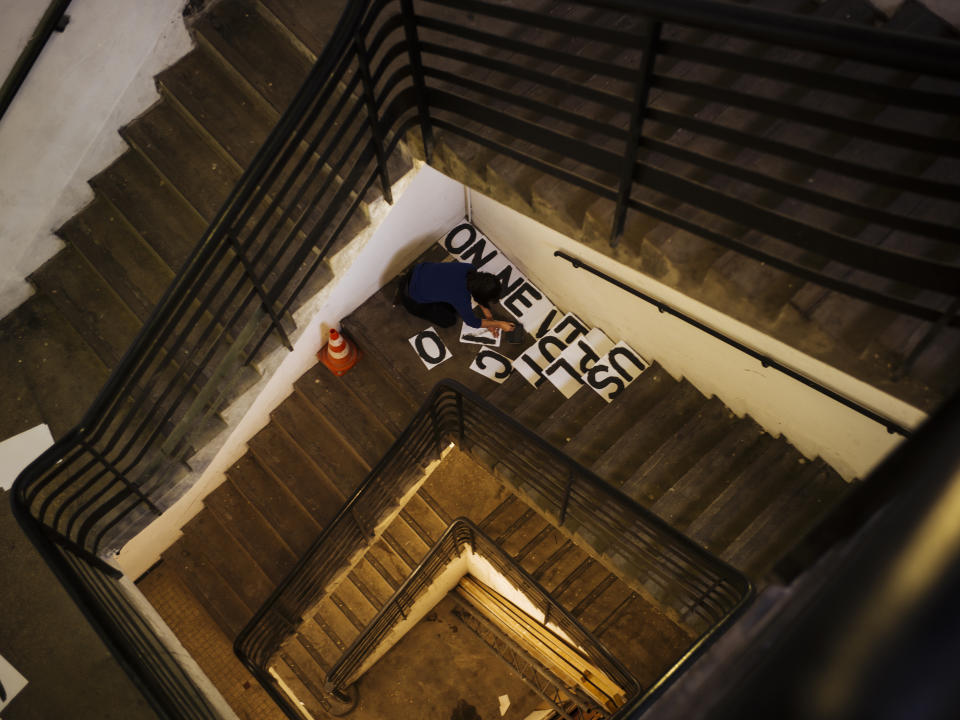 In this Oct. 23 2019 photo, a woman paints some slogans against domestic violence in the stairwell of a building in Paris. Domestic violence rates in France are higher than those in many other European countries, and activists say authorities often fail to protect women. (AP Photo/Kamil Zihnioglu)