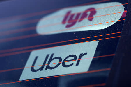 FILE PHOTO: Uber and Lyft signs on a car in Redondo Beach, California, U.S., March 25, 2019. REUTERS/Lucy Nicholson -/File Photo