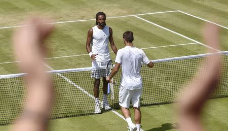 Viktor Troicki of Serbia shakes hands with Dustin Brown of Germany after winning their match as a fan claps at the Wimbledon Tennis Championships in London, July 4, 2015. REUTERS/Toby Melville