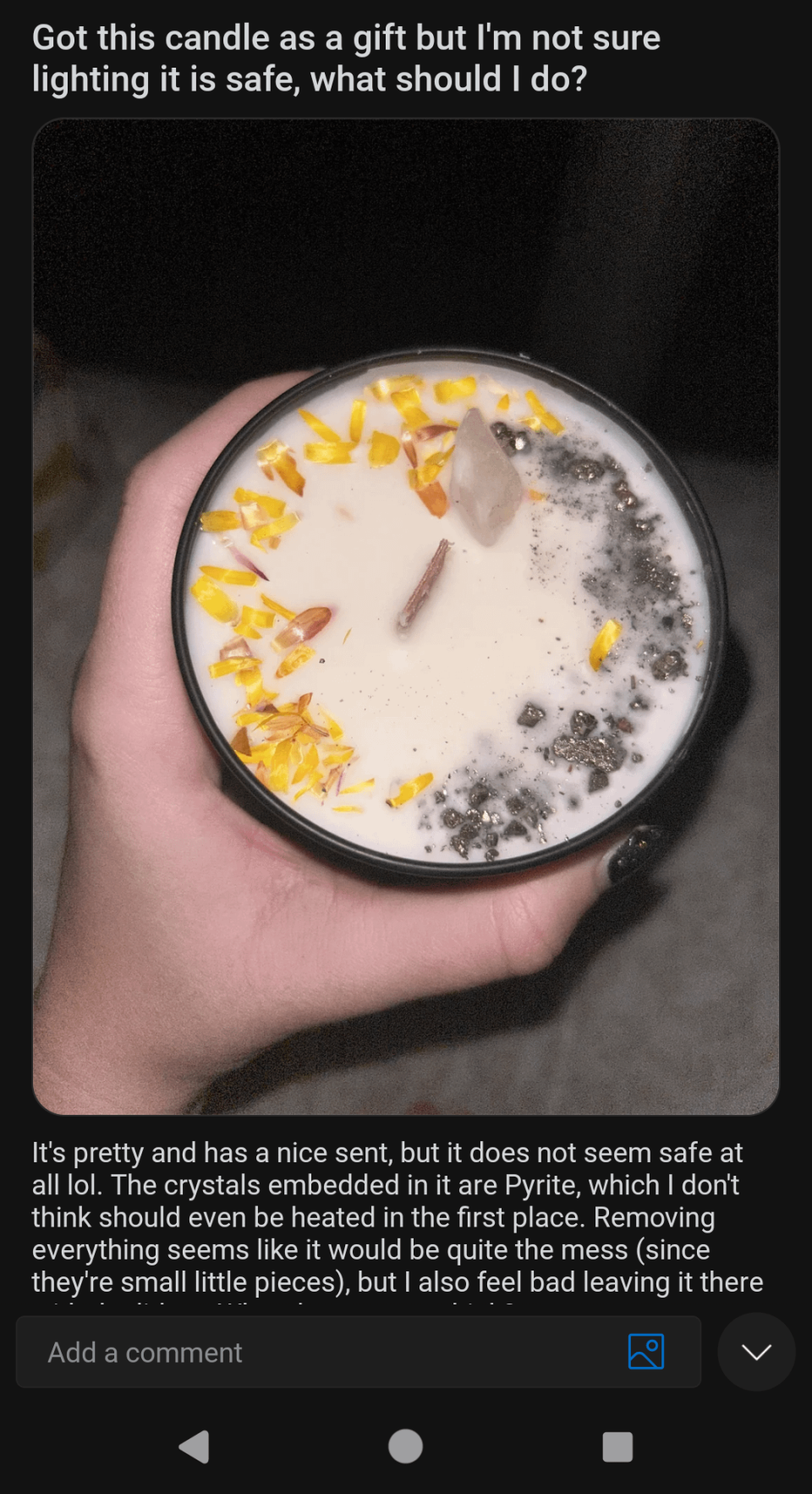 A person is holding a candle with crystals and yellow flower petals. The Reddit caption mentions the crystals are pyrite