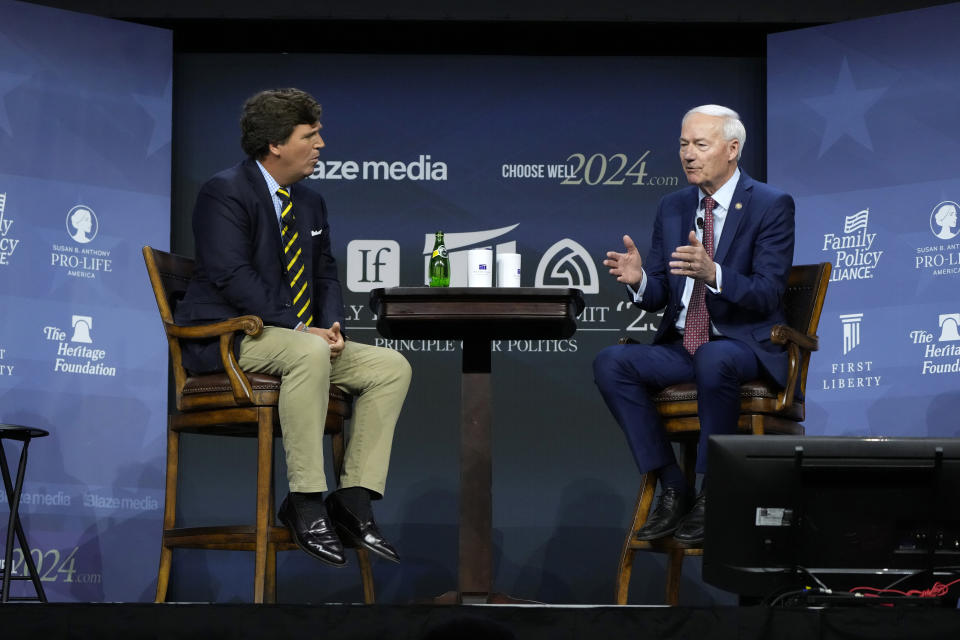 Republican presidential candidate former Arkansas Gov. Asa Hutchinson talks with moderator Tucker Carlson, left, during the Family Leadership Summit, Friday, July 14, 2023, in Des Moines, Iowa. (AP Photo/Charlie Neibergall)