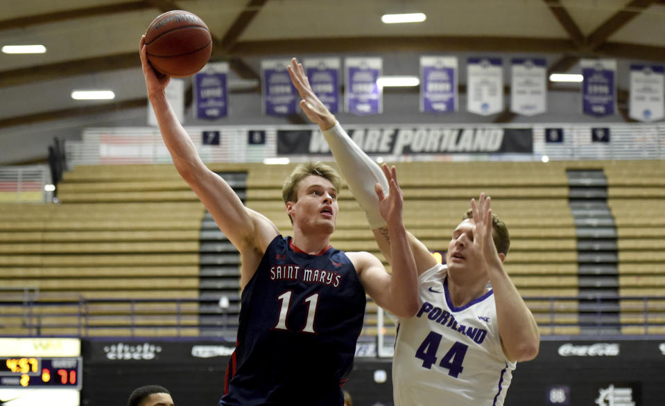 Saint Mary's center Mitchell Saxen, left, shoots next to Portland center Joey St. Pierre during the second half of an NCAA college basketball game in Portland, Ore., Saturday, Feb. 11, 2023. Saint Mary's won 81-64. (AP Photo/Steve Dykes)