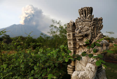 A statue on a bridge is seen as Mount Agung volcano erupts in the background near Kubu, Karangasem Regency, Bali, Indonesia, November 28, 2017. REUTERS/Darren Whiteside