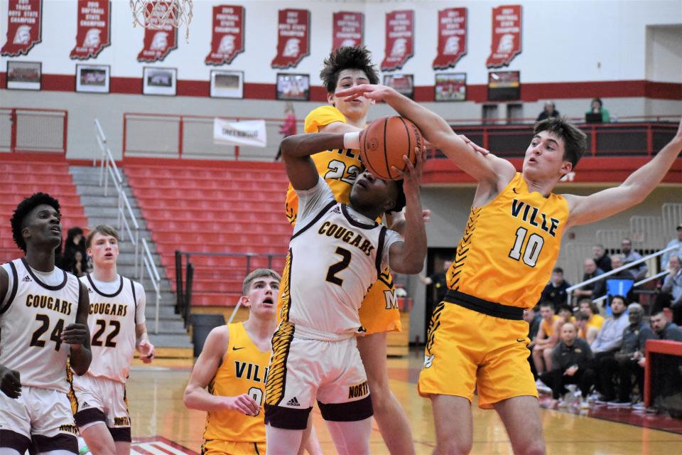 Mooresville's Brevon Burns (22) and AJ DeFur (10) foul Bloomington North's Dawan Daniels during the sectional battle between the Pioneers and Cougars on Feb. 28, 2023.