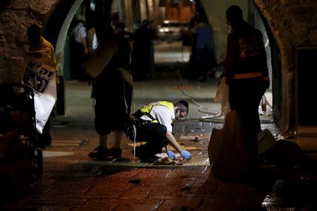 A member of the Zaka Rescue and Recovery team cleans blood stains at the scene where a Palestinian was shot dead after he stabbed and killed two people in Jerusalem's Old City October 3, 2015. REUTERS/Ammar Awad