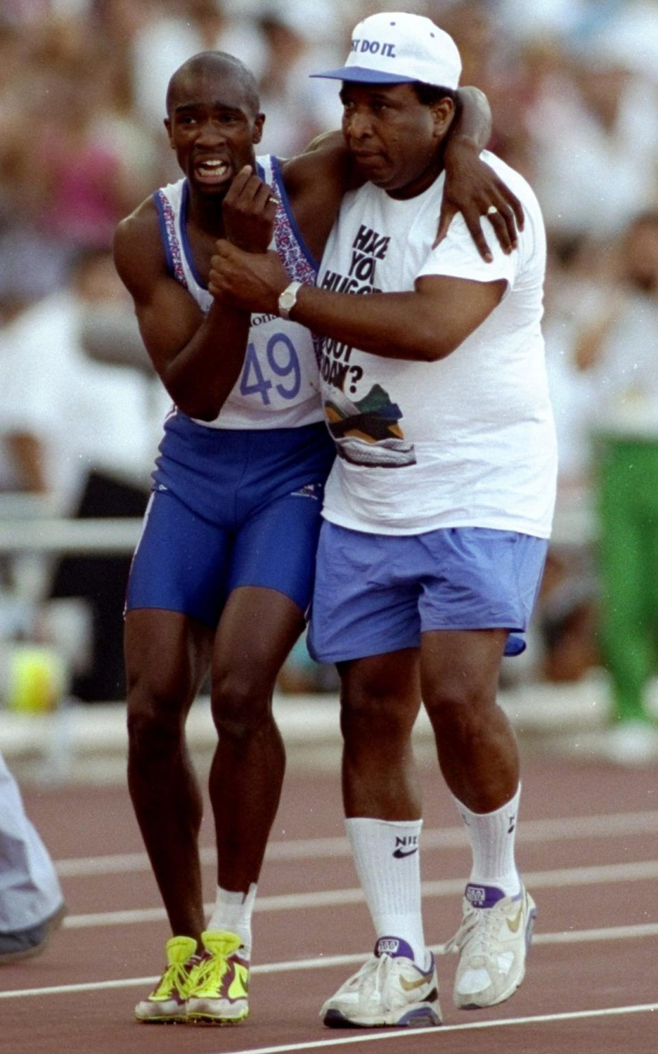 Derek Redmond of Great Britain is helped towards the finish line by his father after suffering an injury in the 400m semi-final at the Barcelona Olympic Games in Spain - Getty Images