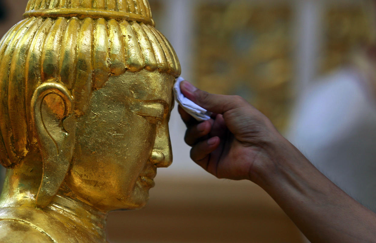 A worshipper places gold paper on a statue of Buddha during Vesak Day celebrations in Singapore. (Reuters file photo)