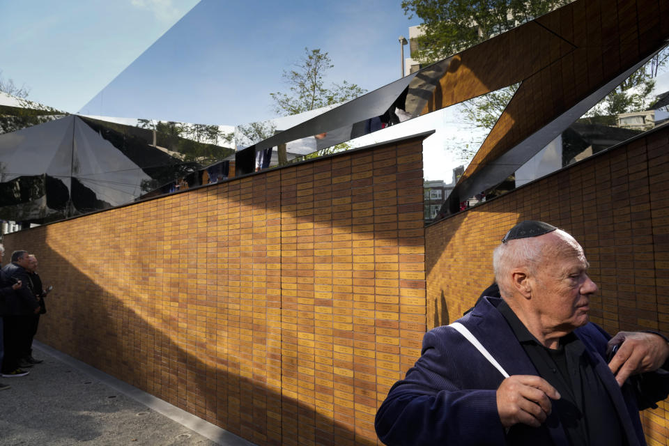 People walk alongs walls with name stones after King Willem-Alexander officially unveiled a new monument in the heart of Amsterdam's historic Jewish Quarter on Sunday, Sept. 19, 2021, honoring the 102,000 Dutch victims of the Holocaust. Designed by Polish-Jewish architect Daniel Libeskind, the memorial is made up of walls shaped to form four Hebrew letters spelling out a word that translates as "In Memory Of." The walls are built using bricks each of which is inscribed with the name of one of the 102,000 Jews, Roma and Sinti who were murdered in Nazi concentration camps during World War II or who died on their way to the camps. (AP Photo/Peter Dejong)