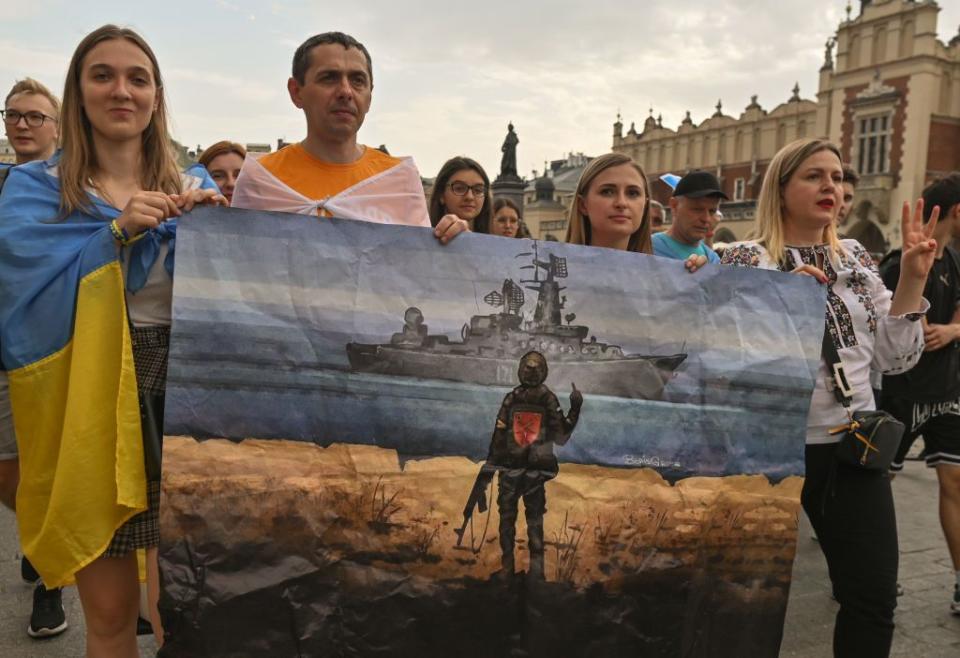 People carry a poster depicting a Ukrainian border guard defending Ukraine's Snake Island in the Black Sea from a Russian advance in Krakow, Poland, on Aug. 24, 2022, amid Russia's full-scale invasion of Ukraine. The Snake Island defenders are famous for having told the advancing Russian forces "Russian warship, go f**k yourself."(Artur Widak/NurPhoto via Getty Images)aa U