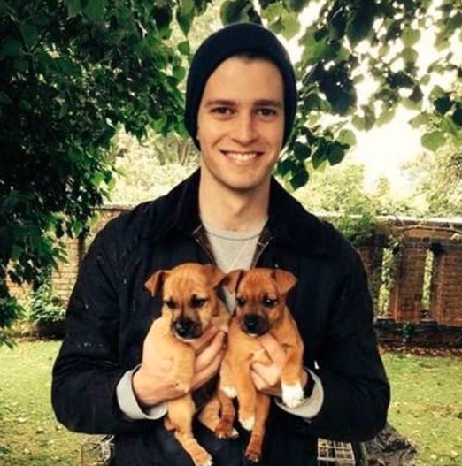 Louis poses in a beanie with two puppies