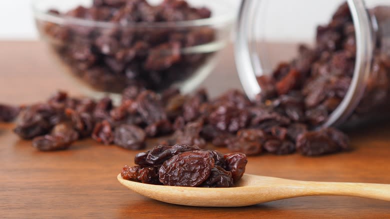 Spoonful of raisins in front of jar of raisins