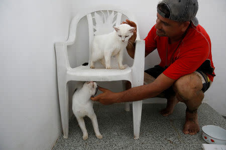 Gary Rosario caresses his cats while they live in a neighbor's house after the area was hit by Hurricane Maria in Yauco, Puerto Rico, September 25, 2017. REUTERS/Carlos Garcia Rawlins