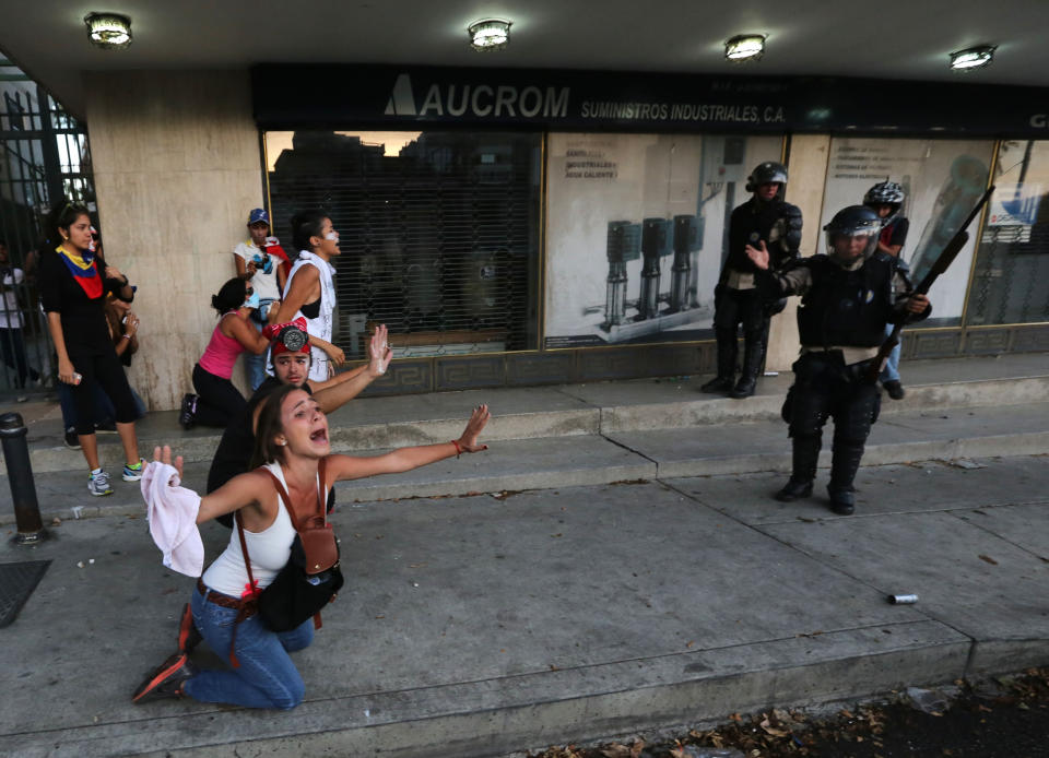 An opposition demonstrator shouts for the National Bolivarian Police (BNP) to not fire tear gas as a member of the force, right, gestures after his superior ordered them to hold their fire, during clashes in Caracas, Venezuela, Saturday, Feb. 15, 2014. Venezuelan security forces backed by water tanks, tear gas and rubber bullets dispersed groups of anti-government demonstrators who tried to block Caracas' main highway Saturday evening. (AP Photo/Fernando Llano)