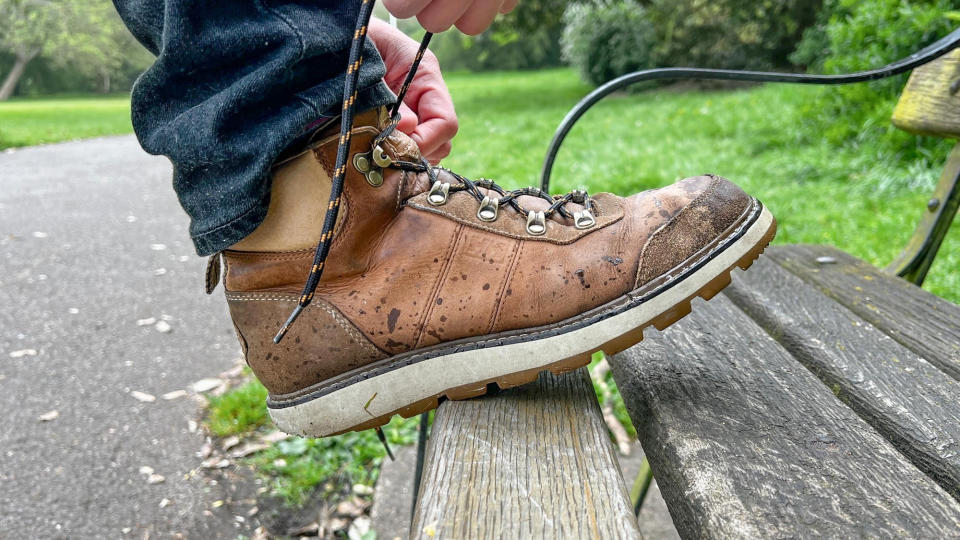 Man lacing up the Helly Hansen Coastal Hiker walking boots on a bench outside