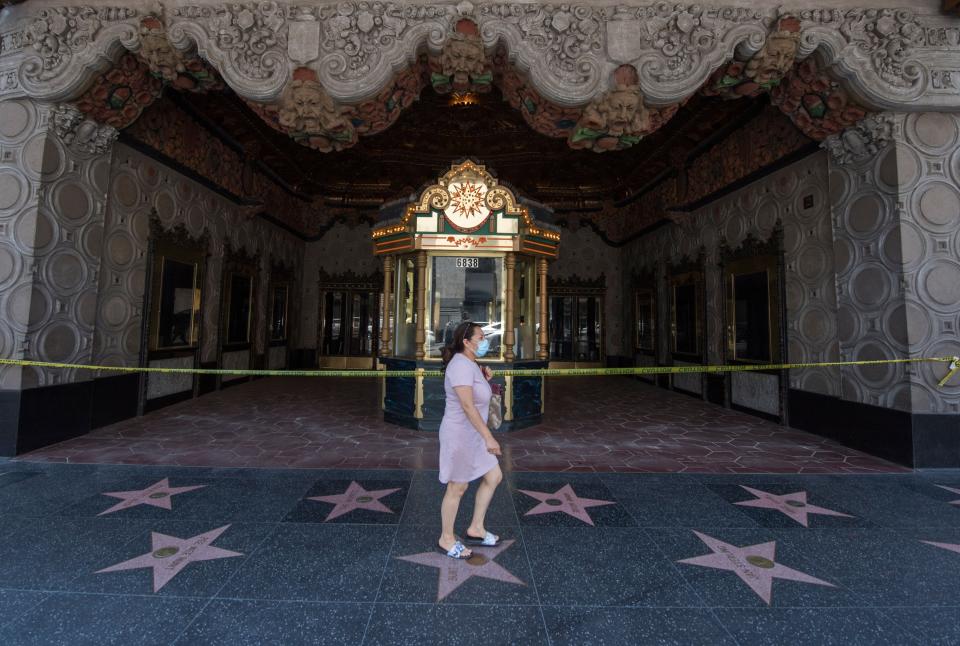 A woman walks past the El Capitan Theater on Hollywood Boulevard in Los Angeles on June 12, 2020. As coronavirus cases in California hit a record high this week, the state is rolling back reopening plans. (Photo: MARK RALSTON via Getty Images)