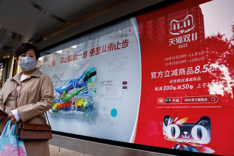 Woman stands near an Alibaba's advertisement promoting Singles Day shopping festival in Beijing