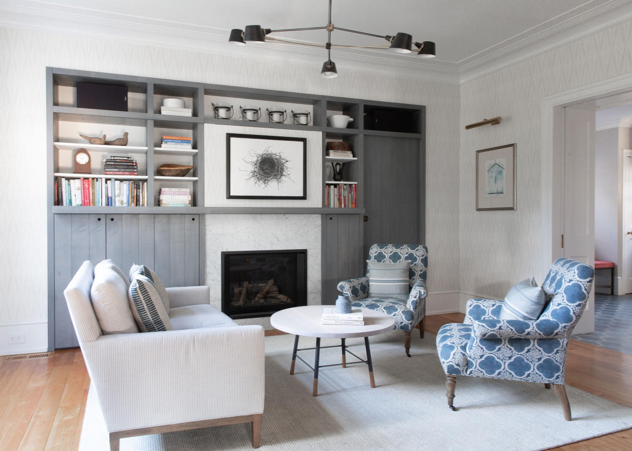  A living room with storage and blue patterned chairs. 