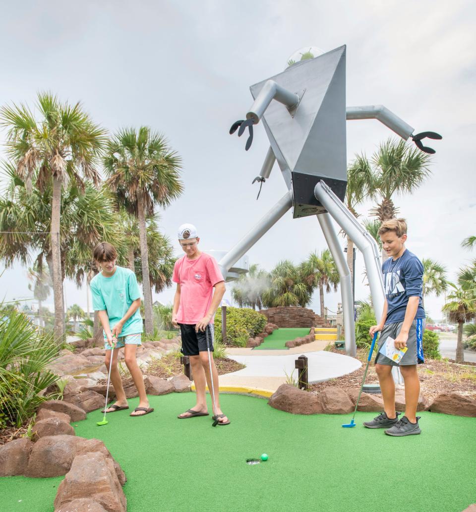 From right, 13-year-olds from Gulf Breeze, Parker Harrelson and Austin Mickler watch as Fisher Kariher's putt just misses the hole at UFO's Mini Golf, Ice Cream, & Arcade in Pensacola Beach on Wednesday, July 8, 2020.  The business is themed and named after the local  infamous UFO reports from the 1980's.