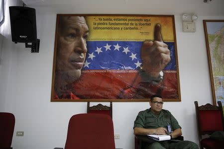 A student sits in front of an image of Venezuela's late President Hugo Chavez during a lecture of the academic course, "Studies of the Thoughts of the Supreme Commander Hugo Chavez" in Caracas November 19, 2014. REUTERS/Carlos Garcia Rawlins