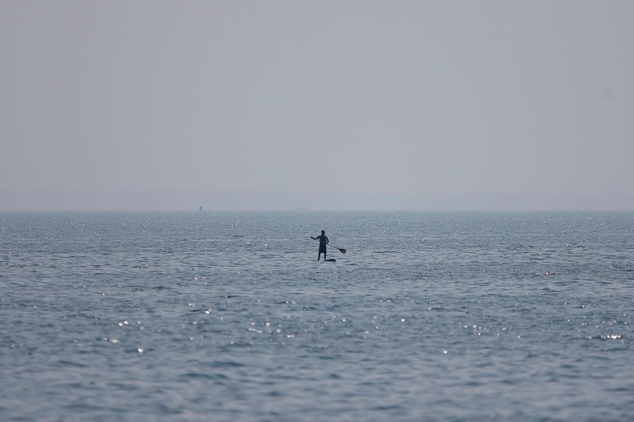 A man paddles his boat in Buzzards Bay on a foggy morning as seen from Fort Taber Park in New Bedford.