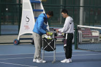 Coaches collect tennis balls after a practice session near the Diamond Court in Beijing, Sunday, Nov. 21, 2021. According to photos released by the organizer, missing tennis star Peng Shuai reappeared in public Sunday at a youth tournament in the court compound in Beijing, as the ruling Communist Party tried to quell fears abroad while suppressing information in China about Peng after she accused a senior leader of sexual assault. (AP Photo/Andy Wong)
