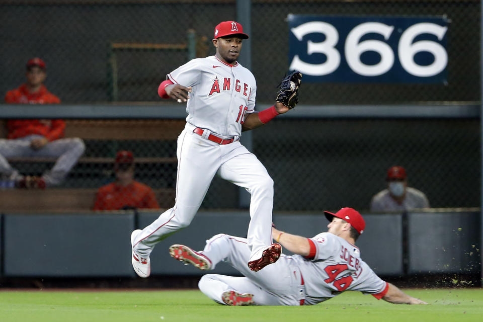 Los Angeles Angels left fielder Justin Upton (10) jumps to avoid right fielder Scott Schebler (44) as they both go to make the out on the fly by Houston Astros' Alex Bregman during the fourth inning of a baseball game Sunday, April 25, 2021, in Houston. (AP Photo/Michael Wyke)