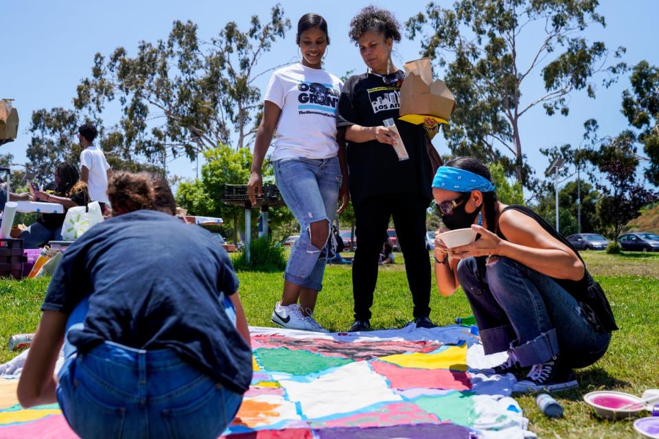 Melina Abdullah chats with her daughter while looking at a banner being painted at a Black Lives Matter event