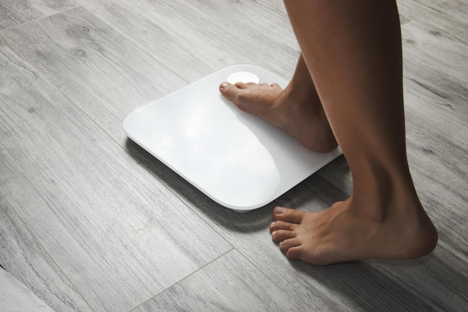 A woman stepping on a scale.