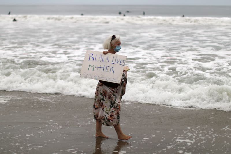 A woman carries a Black Lives Matter sign at The Black Girls Surf paddle-out in memory of George Floyd,who died in Minneapolis police custody, in Santa Monica