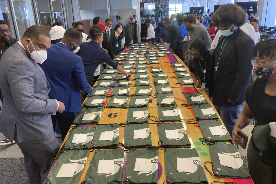 Graduates from the first cohort of the Detroit Apple Developer Academy pick up a gift, a Michigan State University bag, following ceremony held Thursday, June 30, 2022, in Detroit. The inaugural class of the Detroit Apple Developer Academy, a free program that teaches students the fundamentals of coding, design, marketing and project management, celebrated its unique accomplishment during a ceremony held Thursday. (AP Photo/Mike Householder)