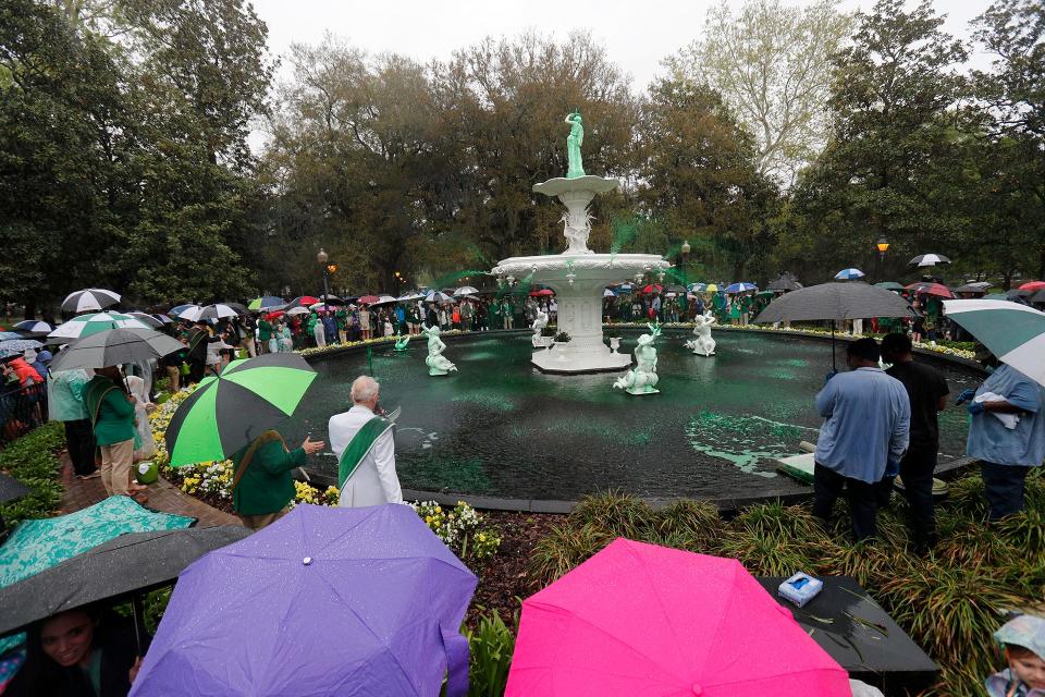 Spectators watched from under the cover of umbrellas as green water begins to spray from the Forsyth Park fountain on Friday March 10, 2023 during the annual St. Patrick's Day Greening of the Fountain.