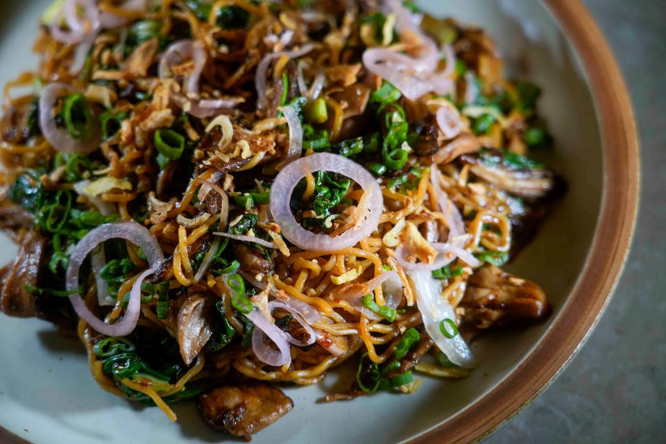 Garlic Indo-Mie Noodles, featuring egg noodles, wild mushrooms, garlic bits, pickled shallot and sambal sweet soy sauce, appears on The Wolf on Broadway's dinner entree menu.