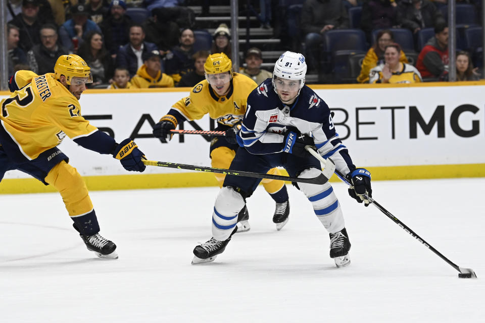 Winnipeg Jets center Cole Perfetti (91) takes the puck past Nashville Predators right wing Nino Niederreiter (22) during the first period of an NHL hockey game Tuesday, Jan. 24, 2023, in Nashville, Tenn. (AP Photo/Mark Zaleski)