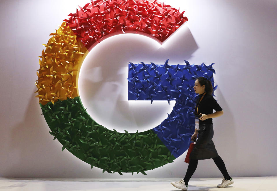 FILE - In this Monday, Nov. 5, 2018 file photo, a woman walks past the logo for Google at the China International Import Expo in Shanghai. Germany’s finance minister on Wednesday welcomed an agreement requiring large companies in the European Union to reveal how much tax they paid in which country. The deal was struck late Tuesday between representatives of the EU’s 27 member states and the European Parliament. (AP Photo/Ng Han Guan, File)