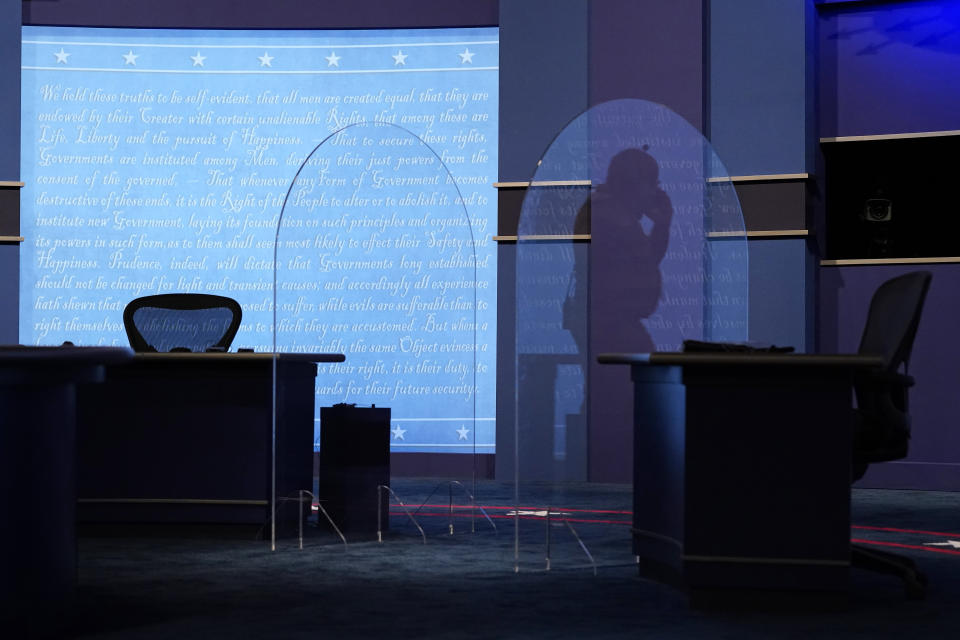 A worker is reflected in a protective plastic panel onstage between tables for Vice President Mike Pence and Democratic vice presidential candidate, Sen. Kamala Harris, D-Calif., as preparations take place for the vice presidential debate in Kingsbury Hall at the University of Utah, Tuesday, Oct. 6, 2020, in Salt Lake City. (AP Photo/Patrick Semansky)