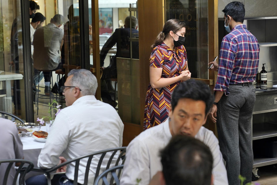 FILE — In this Sept. 13, 2021 file photo. Maitre d' Susanne McDonald, center right, checks a guest's proof of vaccination at a restaurant in midtown Manhattan, in New York. New York City's COVID-19 vaccination mandate for restaurants, gyms and entertainment venues is going so well that only 15 businesses have been fined for not enforcing the policy, Mayor Bill de Blasio said Wednesday, Oct. 13, 2021. (AP Photo/Seth Wenig, File)