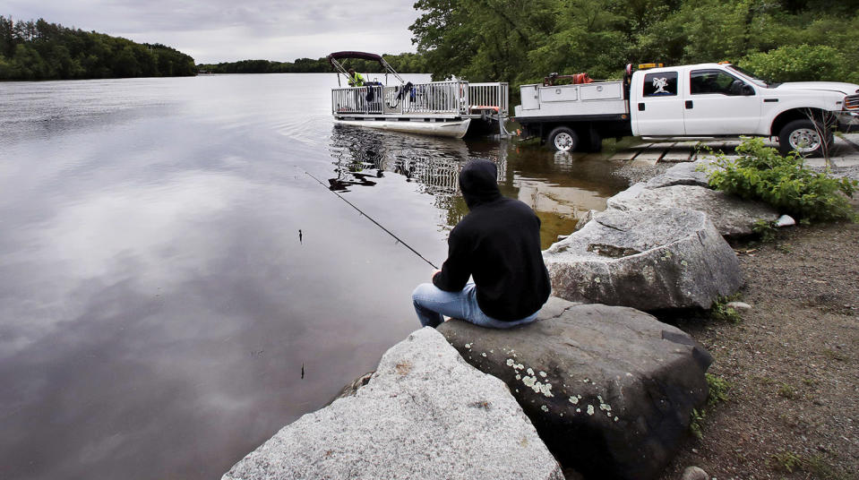 <p>Kevin Garcia fishes along the banks of the Merrimack River as a “Clean River Project” recovery boat is offloaded in Chelmsford, Mass. Syringes left by drug users amid the heroin crisis are turning up everywhere. They hide in weeds along hiking trails and in playground grass, get washed into rivers and onto beaches, and lie scattered about in baseball dugouts and on sidewalks and streets. There are reports of children finding them and getting poked. (Photo: Charles Krupa/AP) </p>