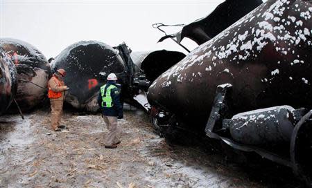 National Transporation and Safety Board (NTSB) member Robert Sumwalt (R) views damaged rail cars at the scene of the BNSF train accident in Casselton, North Dakota January 1, 2014 in this handout provided by NTSB. REUTERS/NTSB/Handout via Reuters