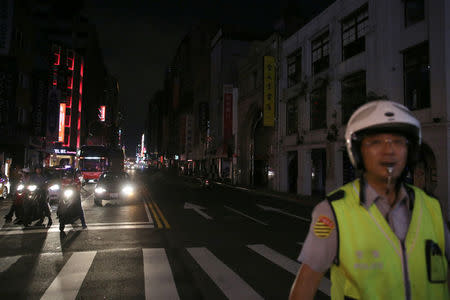 A police stands in front of a building during a massive power outage in Taipei, Taiwan August 15, 2017. REUTERS/Stringer