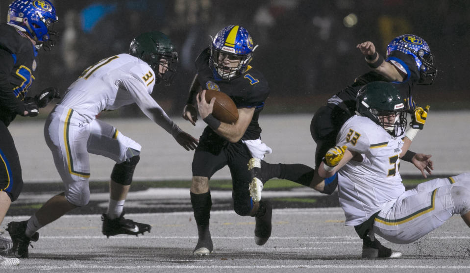 Sutter Union's Cory McIntyre, center, runs past Paradise's Josh Alvies, left, and Ashton Wagner, right, during the first quarter of a Northern Section Division III high school football playoff game in Yuba City, Calif., Saturday, Nov. 30, 2019. Paradise had an undefeated season and made it to the section championship game a year after the deadliest wildfire in California history that killed dozens and destroyed nearly 19,000 buildings including the homes of most of the players. (AP Photo/Rich Pedroncelli)