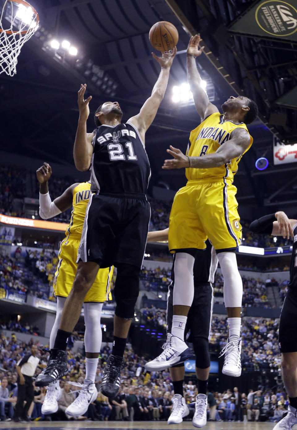 San Antonio Spurs forward Tim Duncan (21) grabs a rebound in front of Indiana Pacers guard Rasual Butler in the first half of an NBA basketball game in Indianapolis, Monday, March 31, 2014. (AP Photo/Michael Conroy)